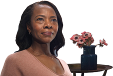 Woman smiling with flowers behind her.